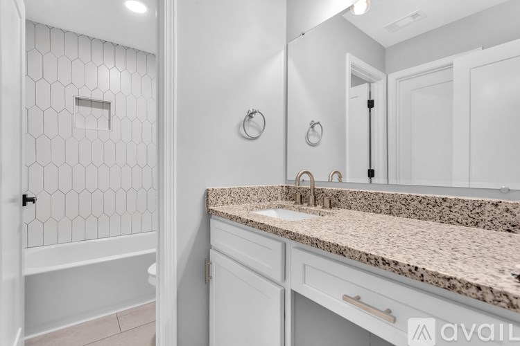 A bathroom with a marble countertop and a hexagonal tile shower.