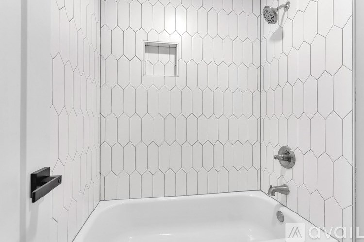 A white tiled shower with a white tub and a white shower head.