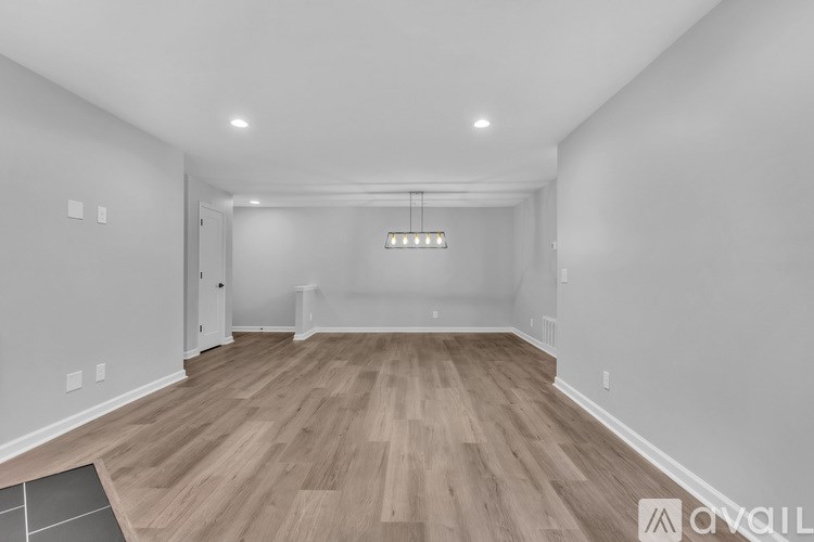 A spacious room with wooden flooring and a light fixture hanging from the ceiling.