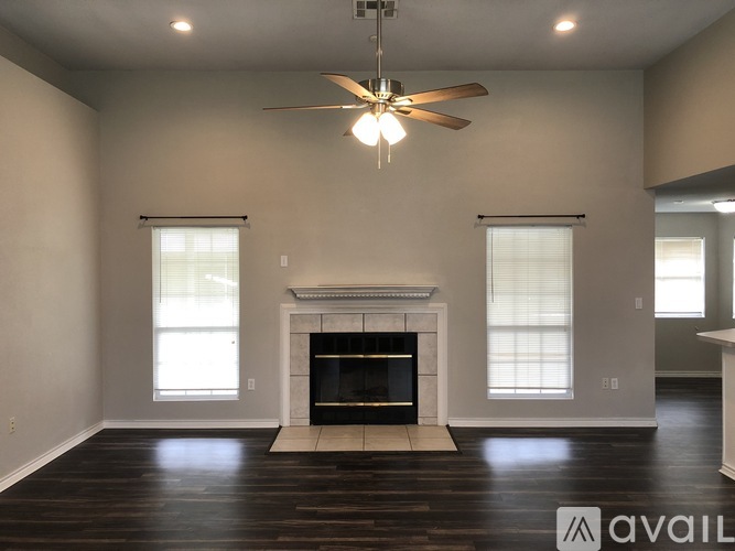 A living room with a fireplace and a ceiling fan.