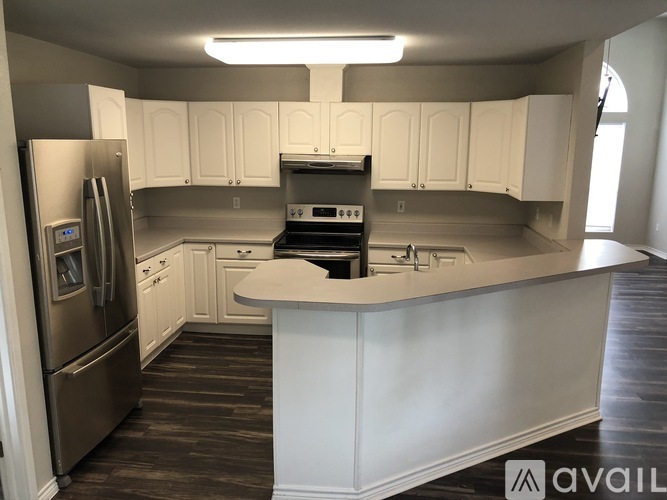 A kitchen with white cabinets and a stainless steel refrigerator.