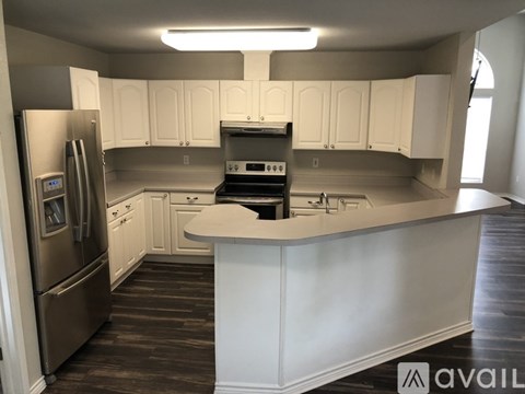 A kitchen with white cabinets and a stainless steel refrigerator.