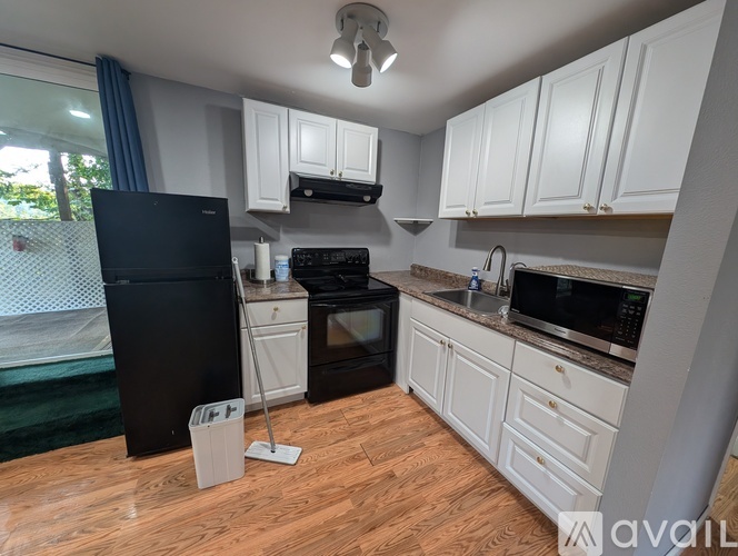 A kitchen with a black fridge and white cabinets.