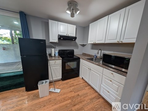 A kitchen with a black fridge and white cabinets.