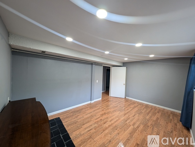A room with wooden flooring and a curved ceiling with lights.