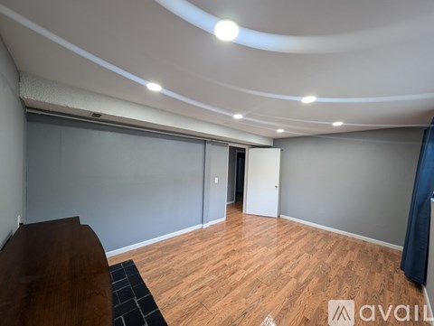 A room with wooden flooring and a curved ceiling with lights.