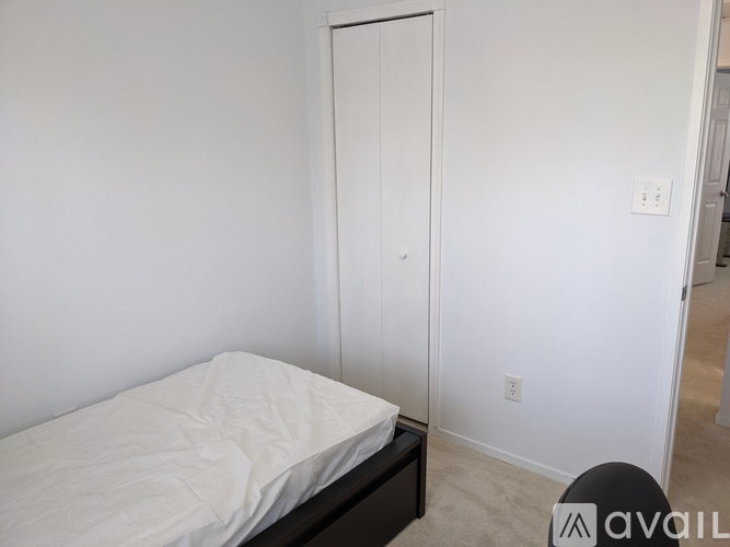 A bedroom with a bed, a door, and a light switch on the wall.
