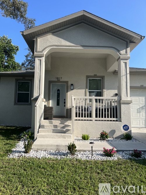 A small white house with a front porch and a mailbox on the right side.