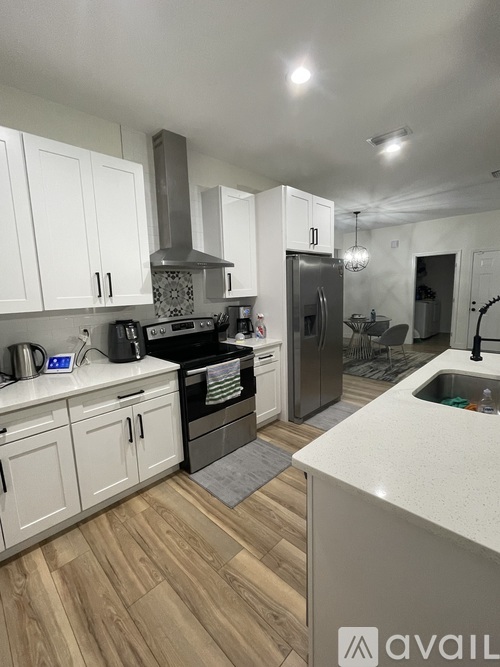 A kitchen with white cabinets and a wooden floor.