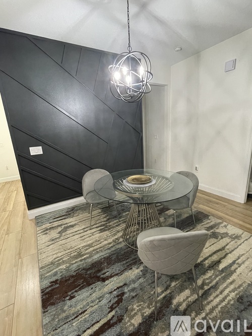 A modern dining area with a glass table and grey chairs.