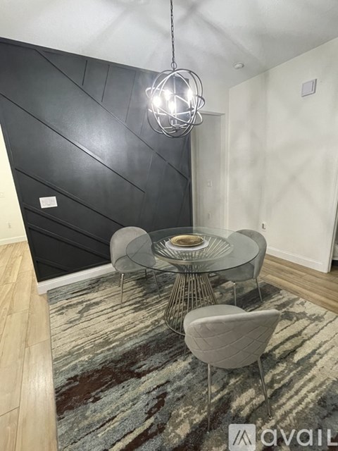 A modern dining area with a glass table and grey chairs.