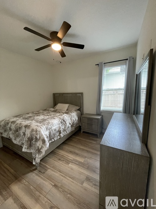 A bedroom with a bed, nightstand, and a ceiling fan.