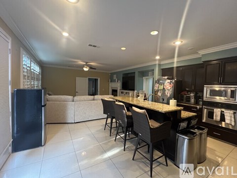 A kitchen with a black refrigerator, a marble countertop, and a dining table with chairs.