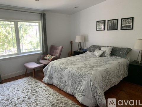 A bedroom with a large bed and a chair by the window.