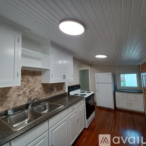 A kitchen with white cabinets and a wooden floor.
