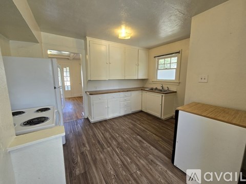 A kitchen with white cabinets and a wooden floor.