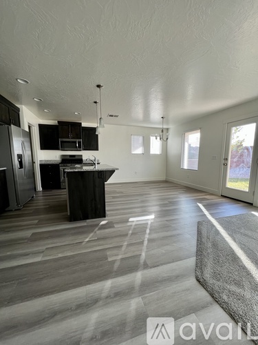 A spacious kitchen and living room with wooden flooring and white walls.