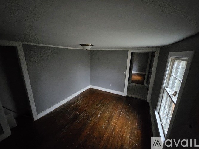 A room with wooden floors and a window on the right side.