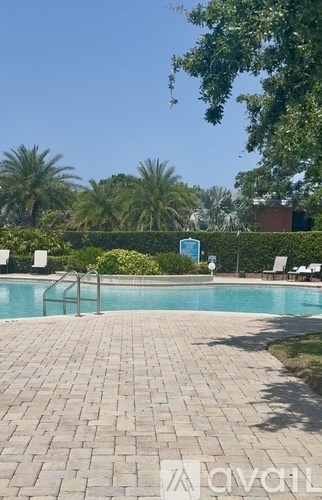 A pool surrounded by a brick patio and palm trees.