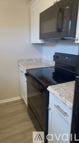 A kitchen with a black countertop and a white wall.