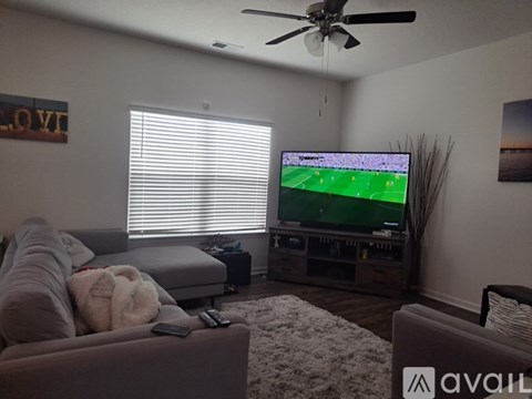 A living room with a grey couch and a television playing a soccer game.