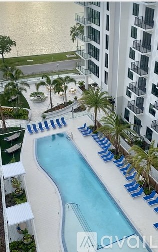 A pool surrounded by lounge chairs and palm trees.