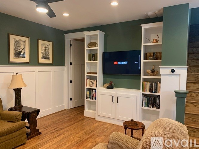A living room with a television, bookshelves, and a chair.