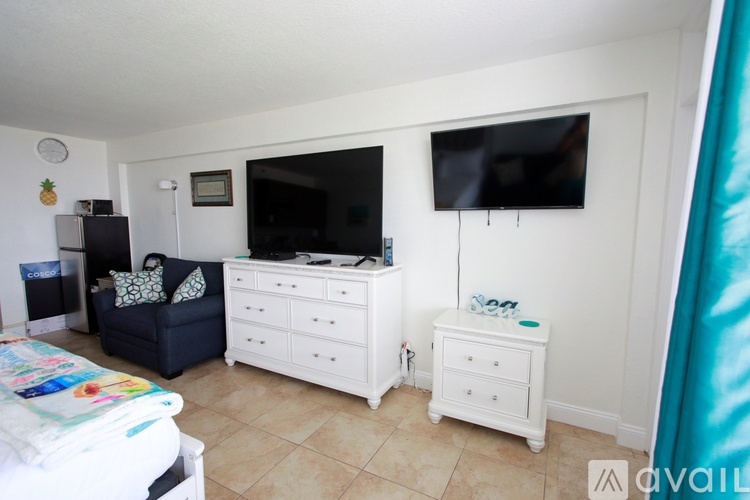 A bedroom with a white dresser and a television mounted on the wall.