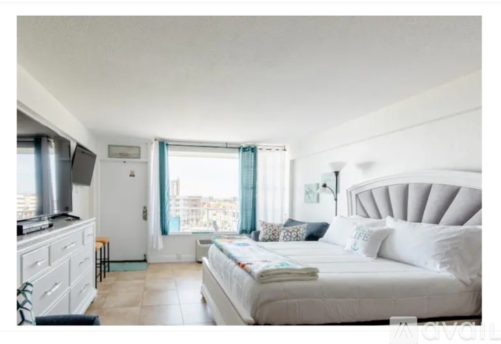 A bedroom with a large bed and a window overlooking a cityscape.