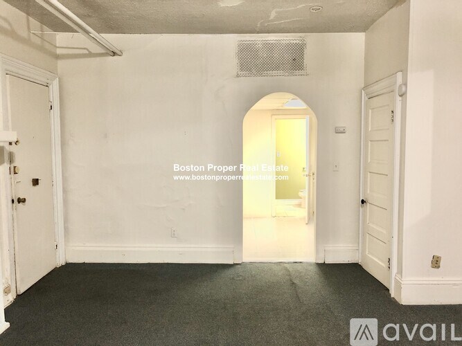 A room with a door on the left and an arched doorway on the right.