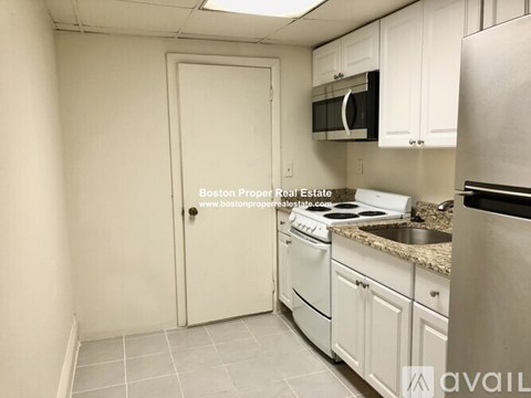A kitchen with white cabinets and a stainless steel refrigerator.