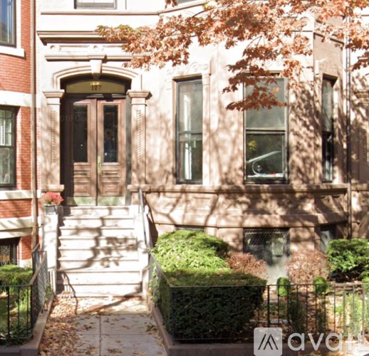 A brown door is on the left side of a white building.
