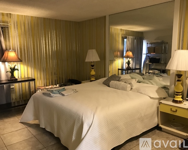 A bedroom with a large bed and two lamps.