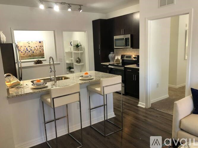 A kitchen with white bar stools and a black fridge.