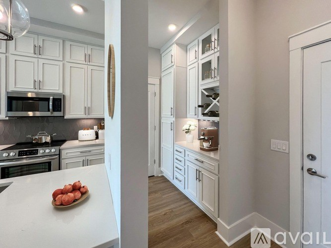 A kitchen with white cabinets and a wooden floor.
