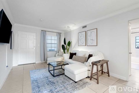 A living room with a white couch and a blue rug.