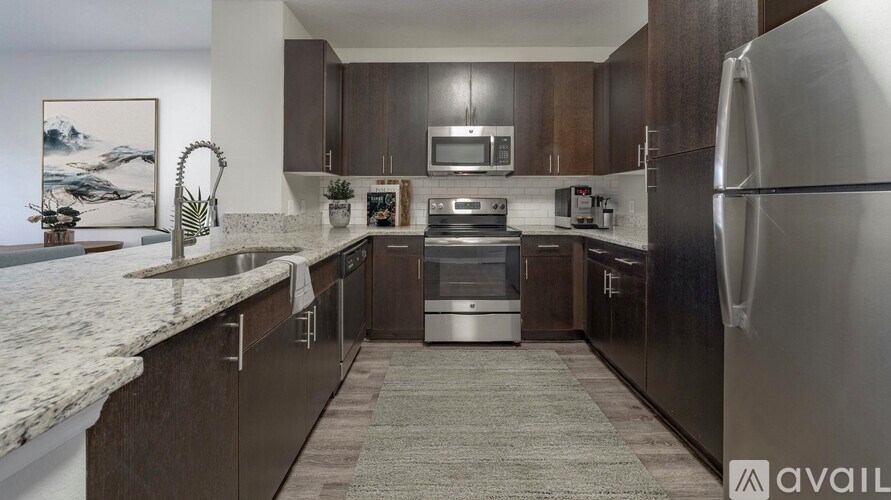A modern kitchen with dark wood cabinets and stainless steel appliances.