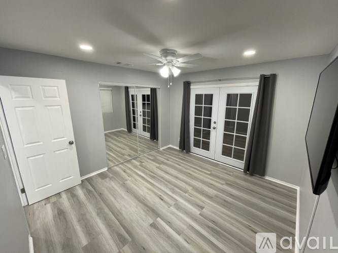 A room with a white door and a ceiling fan.