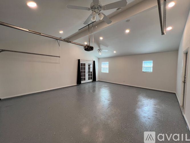 A spacious room with wood flooring and a ceiling fan.