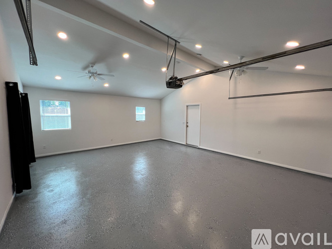 A room with a ceiling fan and a flat screen TV mounted on the wall.