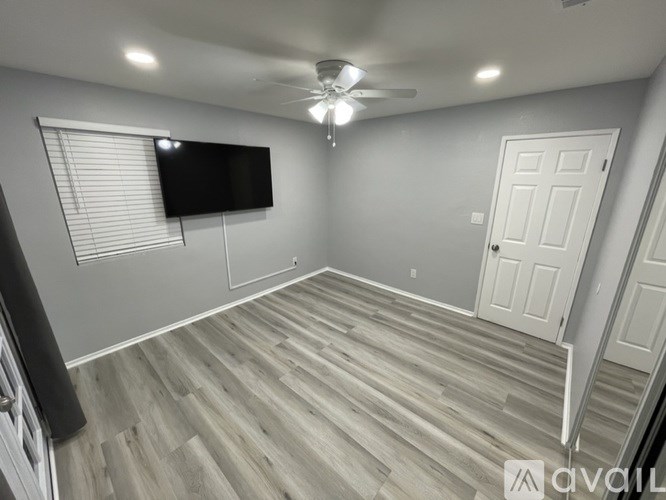 A room with a ceiling fan and a flat screen TV mounted on the wall.