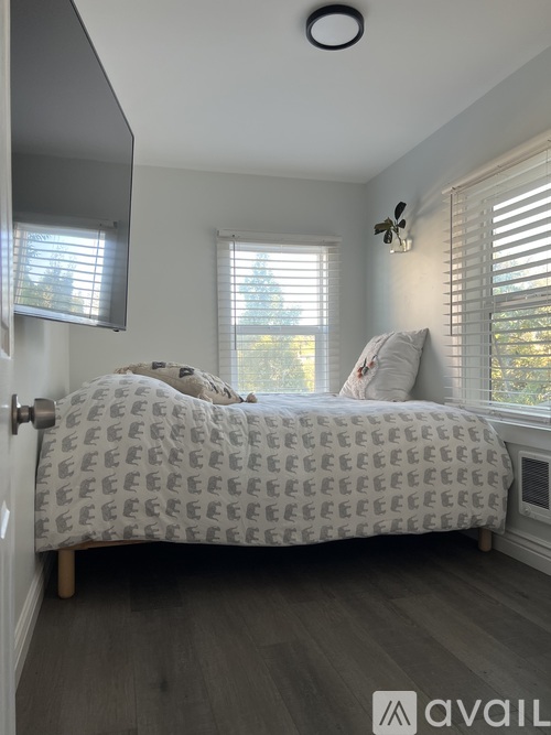 A bedroom with a bed and a window with blinds.
