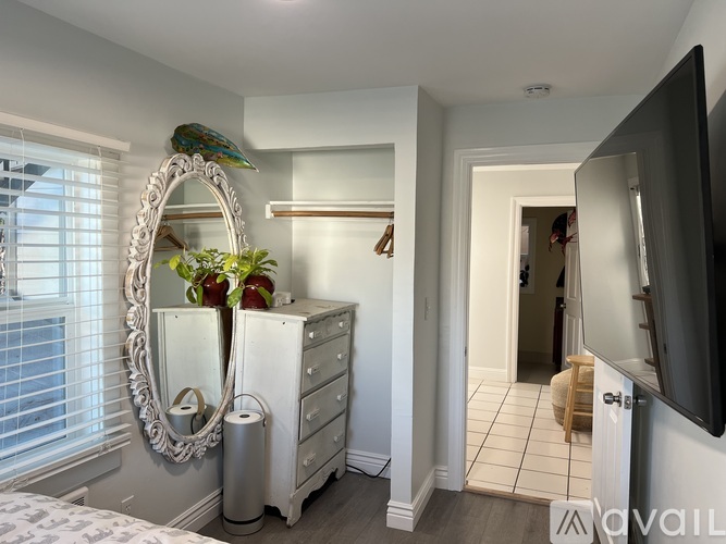 A bedroom with a bed, dresser, mirror, and a television.