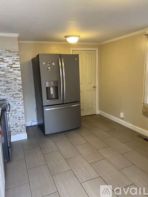 A kitchen with a black fridge and a stone wall.
