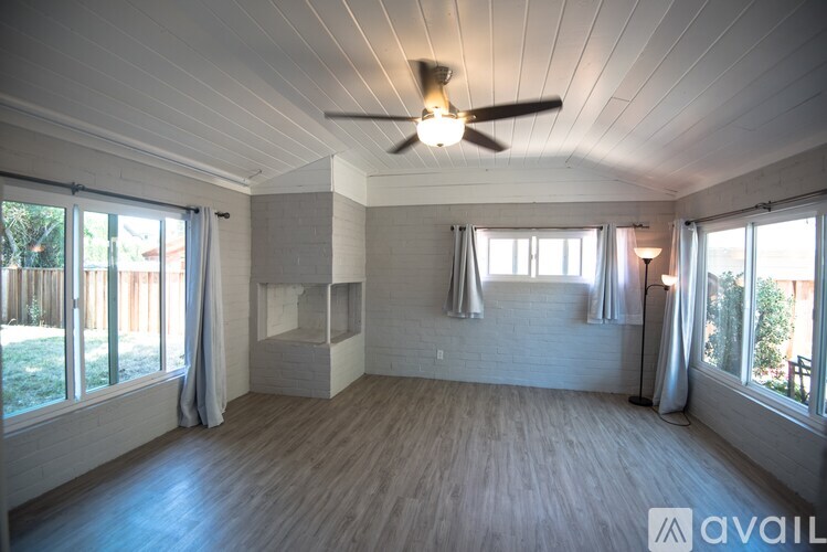A spacious room with a ceiling fan and large windows.