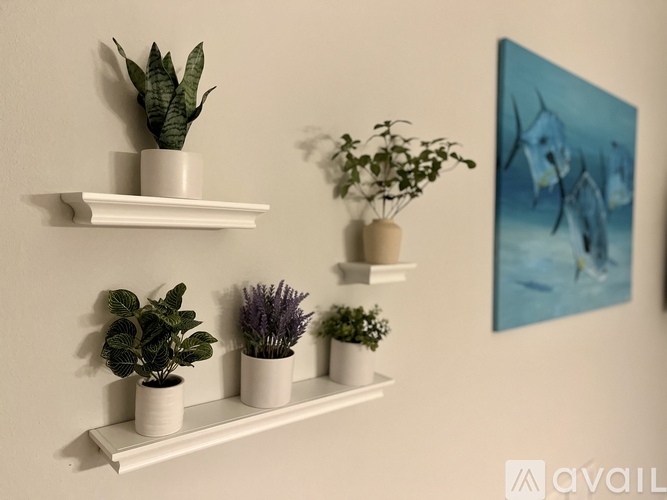 A wall with a shelf holding potted plants and a painting.