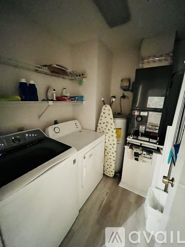 A small kitchen with white appliances and a black fridge.