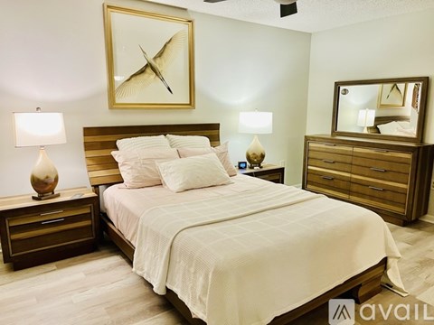 A bedroom with a large bed, a nightstand with a lamp, and a dresser with a mirror.