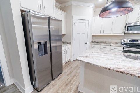 A kitchen with a stainless steel refrigerator and a marble countertop.