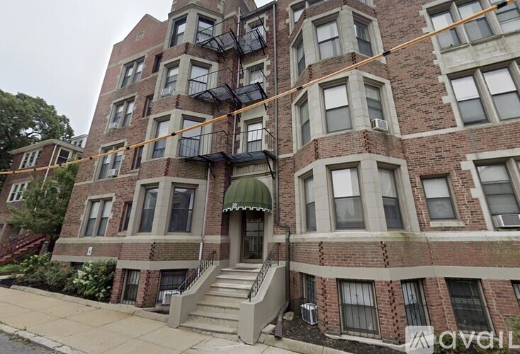 A multi-story brick building with a green awning and a balcony on the second floor.